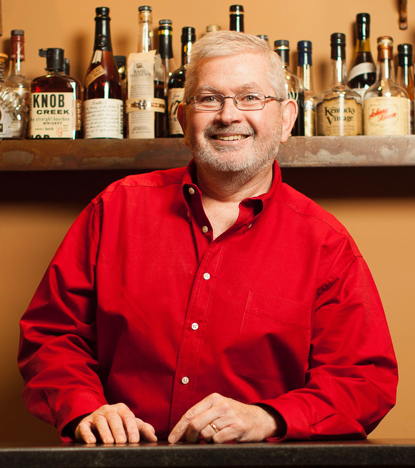 Chris-Zaborowski in front of a shelf of bourbon bottles